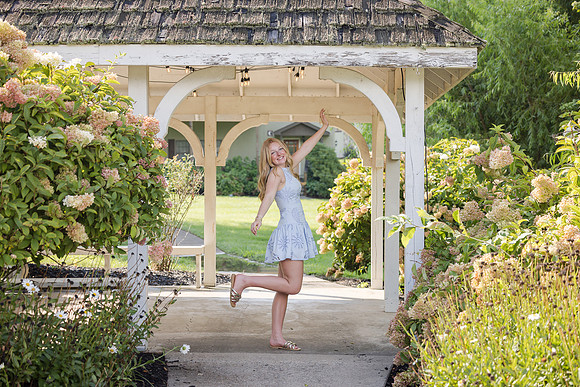 Senior Portraits at Lake Chatuge in North Georgia showing a young high school senior posing in front of flowering hydrangeas and underneath a pergola on the grounds of The RIdges REsort.